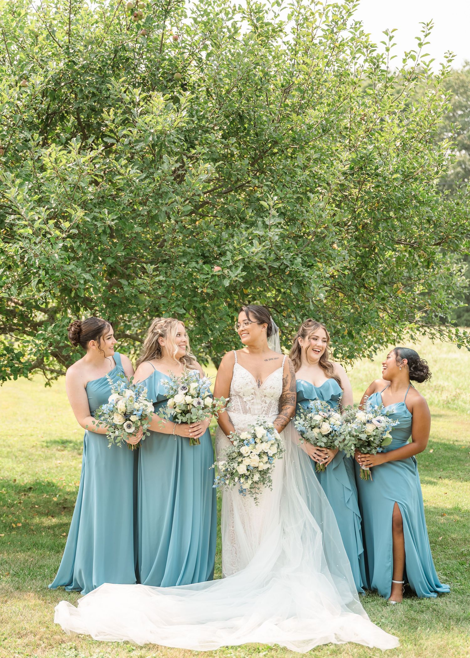 A series of wedding party photos show bridesmaids in dusty blue dresses standing together outdoors in a garden setting.