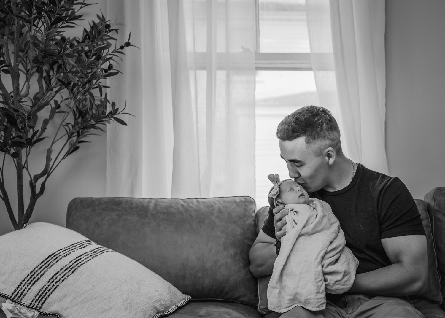 Tender moment on grey couch with natural window light.