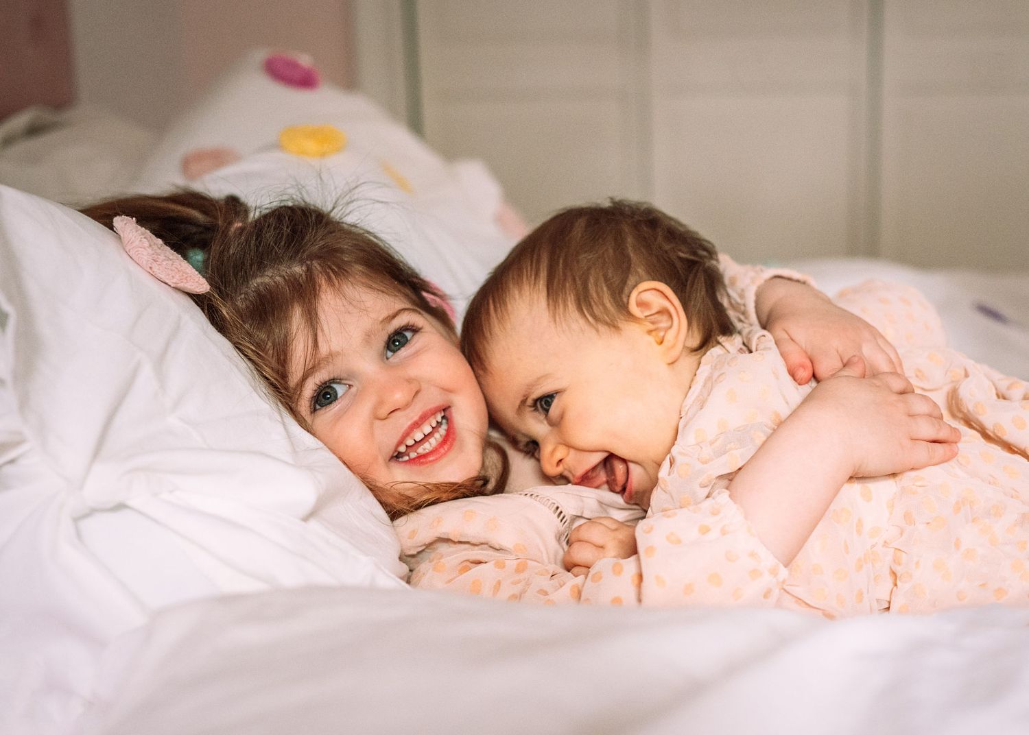 Two children sharing a sweet moment while lying in bed together.