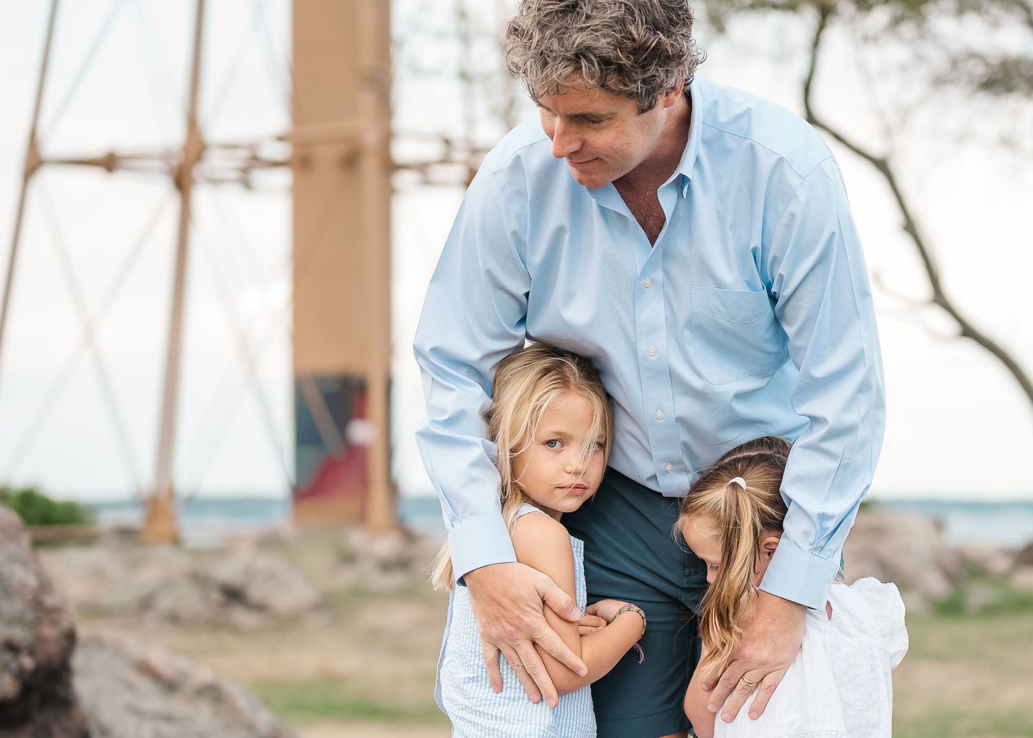 A couple in light blue and navy outfits embrace outdoors during a romantic photoshoot session.