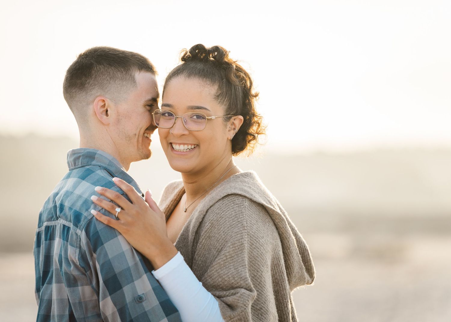 An intimate engagement photo showing a close-up of a couple laughing together outdoors.