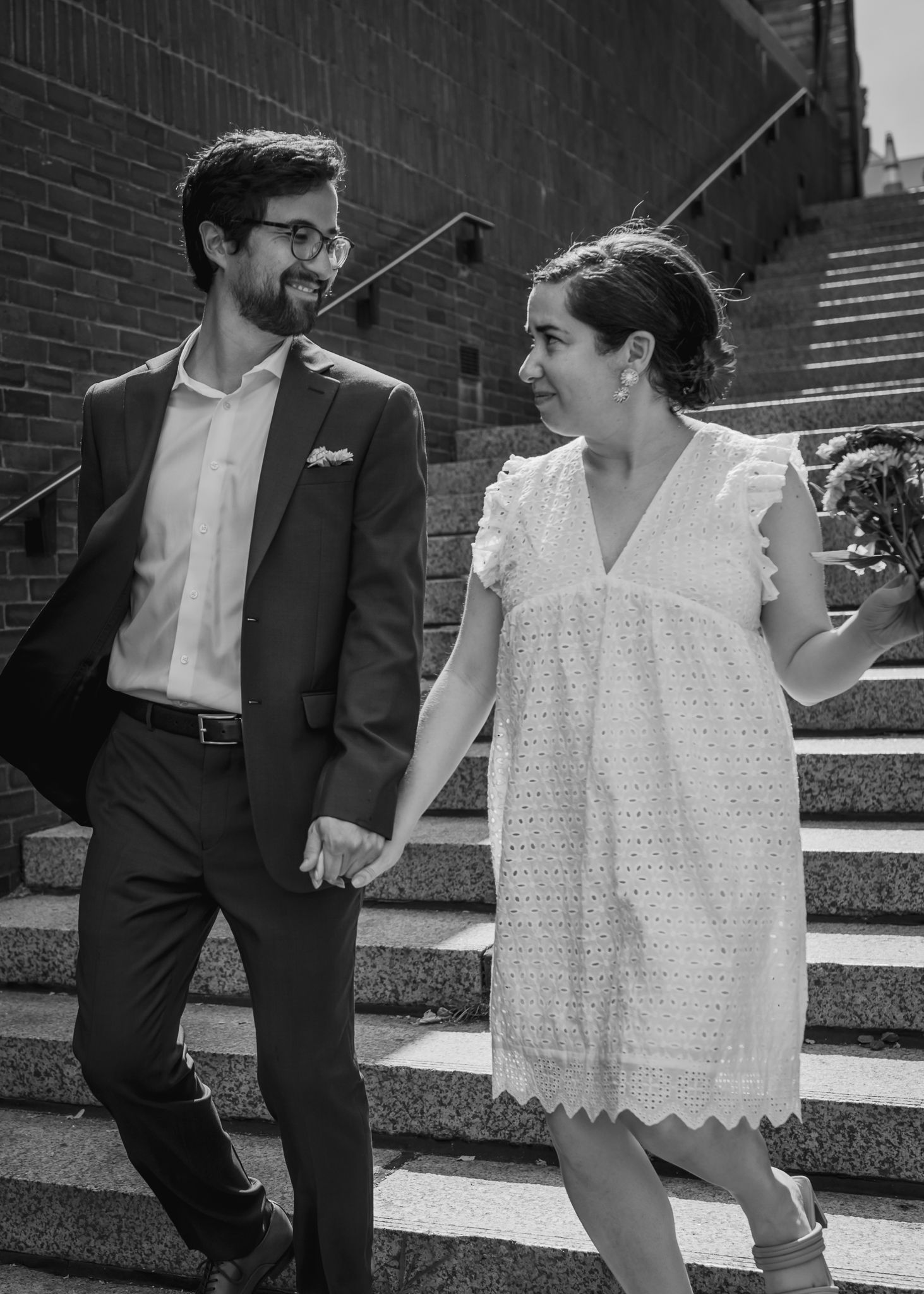 A candid black and white portrait of a couple on stone steps sharing a moment together.