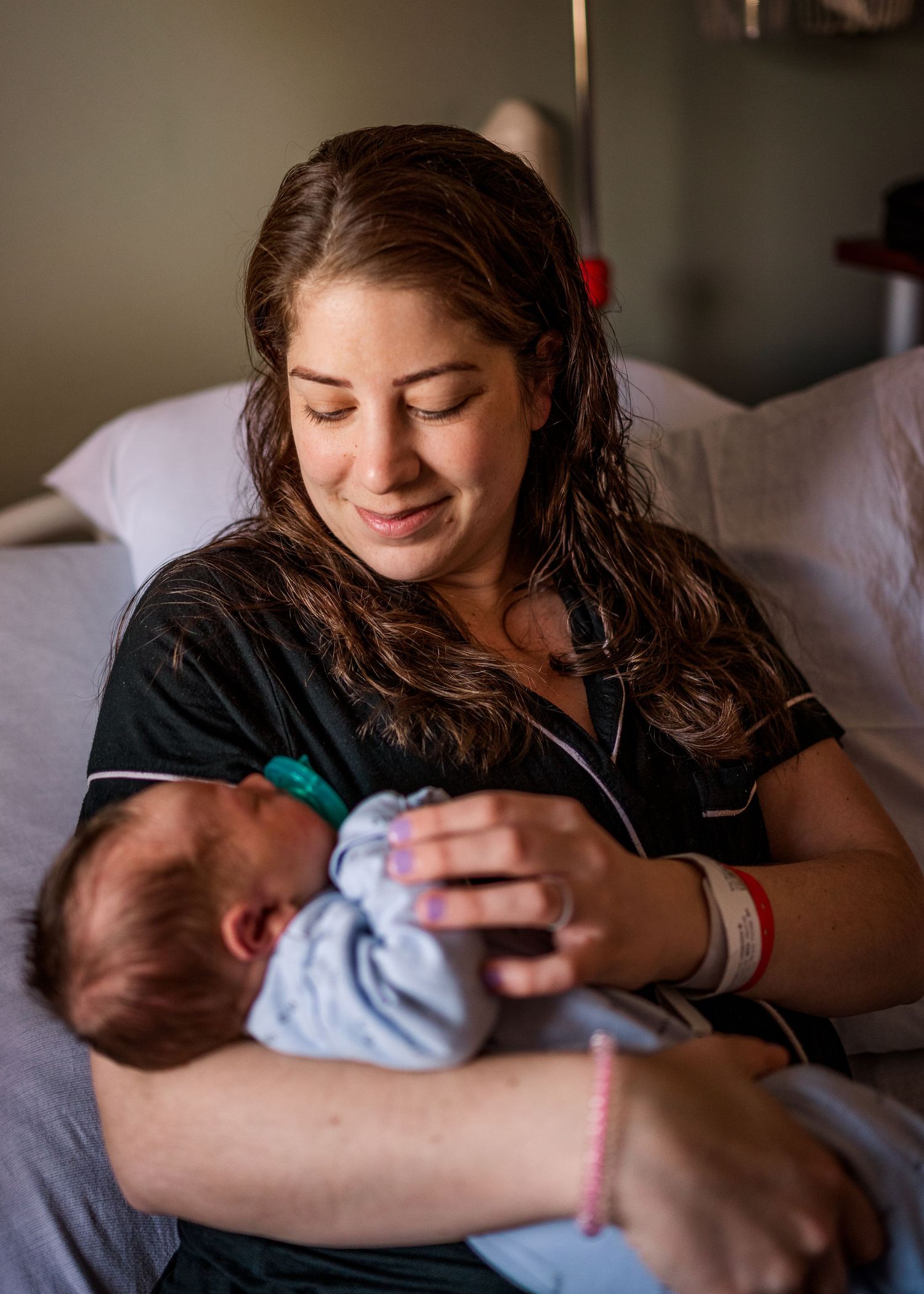 A nurturing moment shared between parent and infant in natural window light.