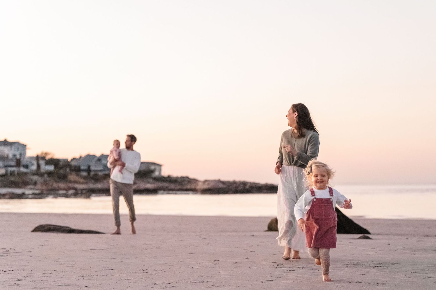 A family walks along a scenic beach at sunset while holding hands and enjoying quality time together.