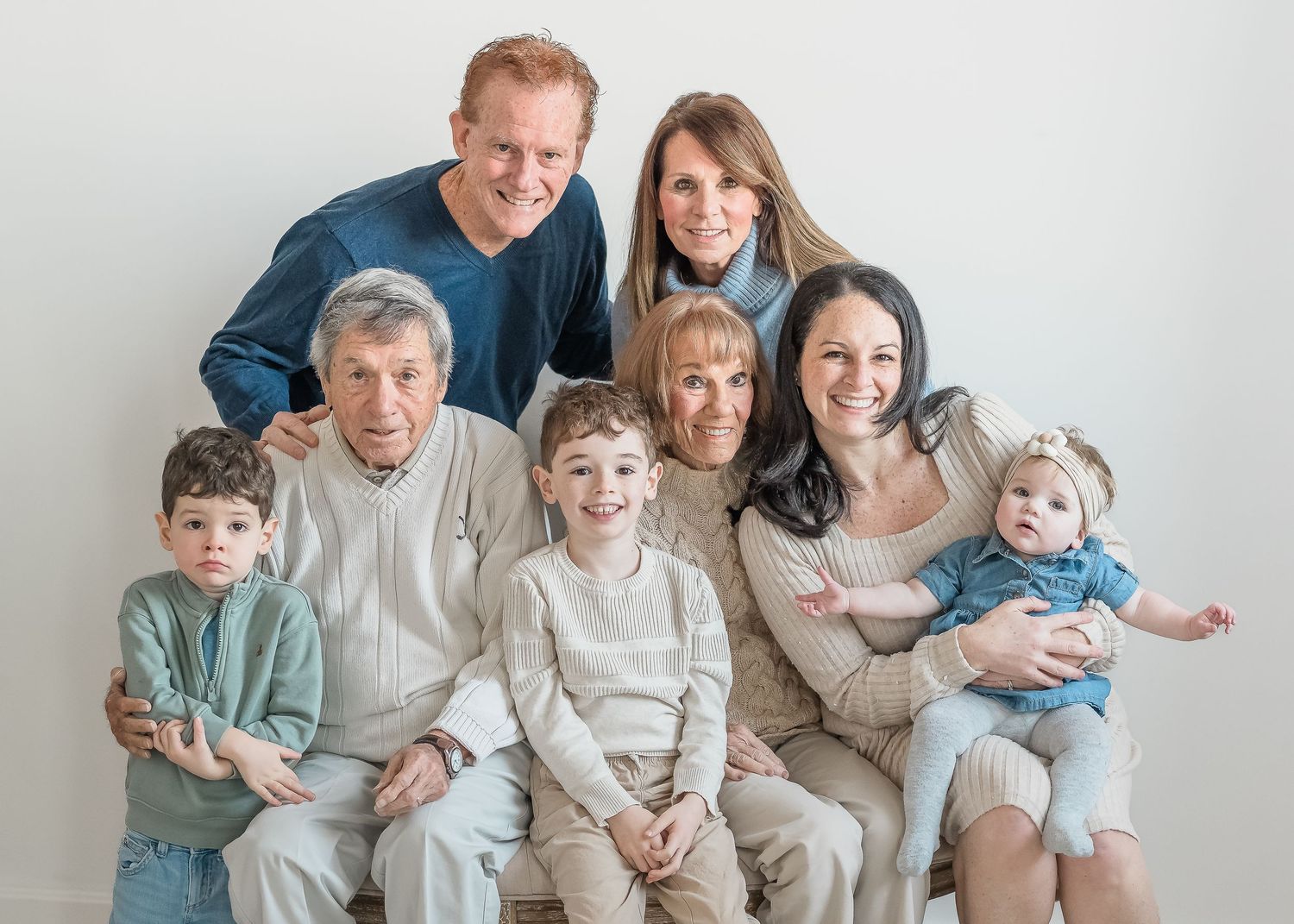 A series of five family portrait photos showing a group in coordinated neutral-colored outfits sitting together on a couch.