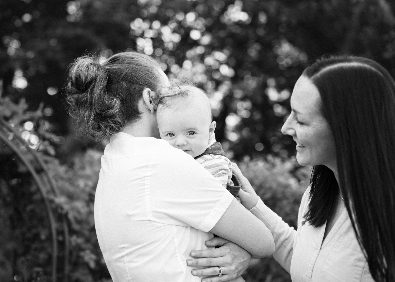A black and white portrait of a family sharing a tender moment together outdoors.