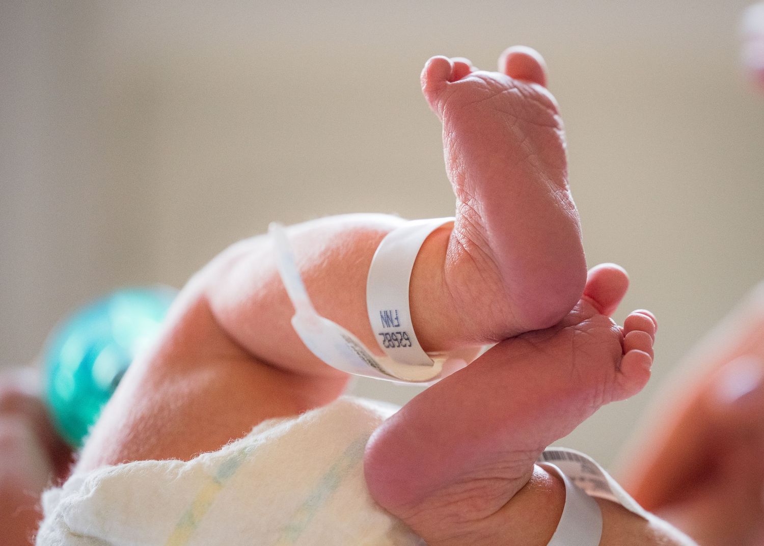 Close-up of tiny newborn baby foot with hospital ID bracelet.