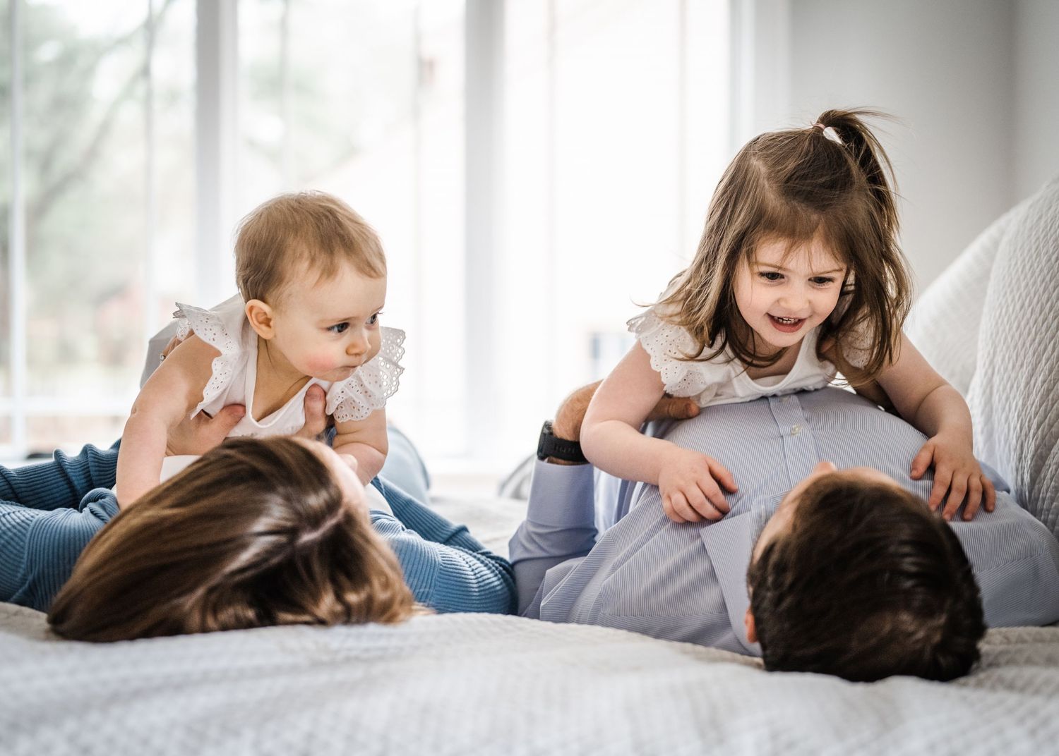 A playful family moment on a bed with children and adults.