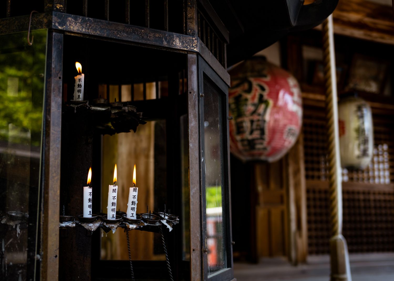 Traditional Japanese lantern in wooden temple with paper screens and red decorative elements.