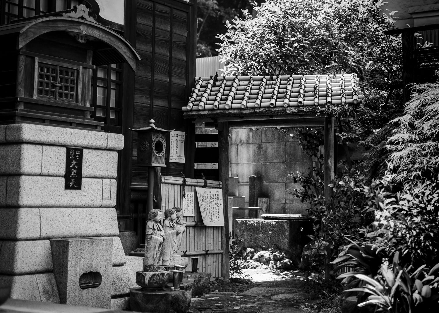 Black and white photograph of traditional Japanese architecture with tiled roofs and garden elements.