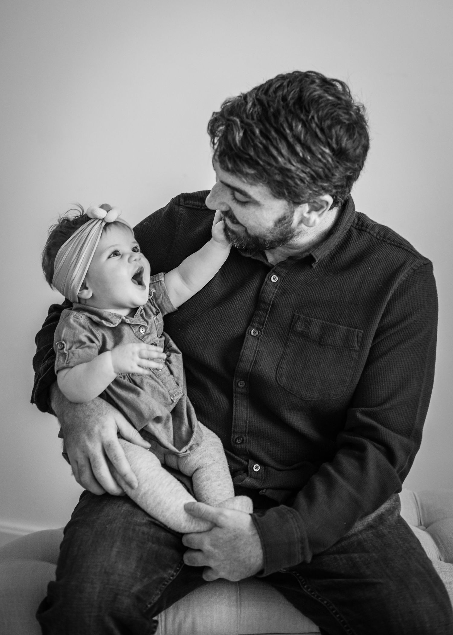 Black and white photo of parent and infant sharing tender moment while sitting together.