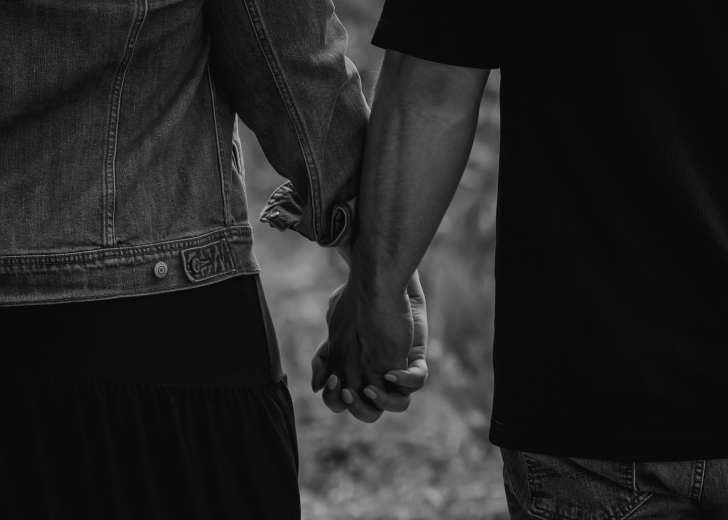 Black and white close-up of couple holding hands showing emotional connection.