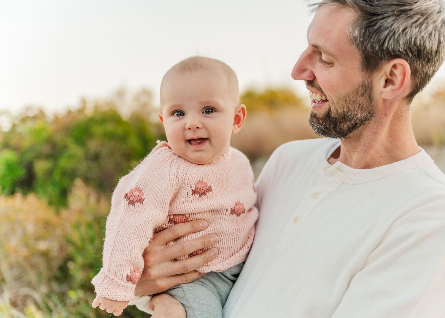 A parent and baby share joyful moments together in a series of outdoor photos with soft natural lighting.