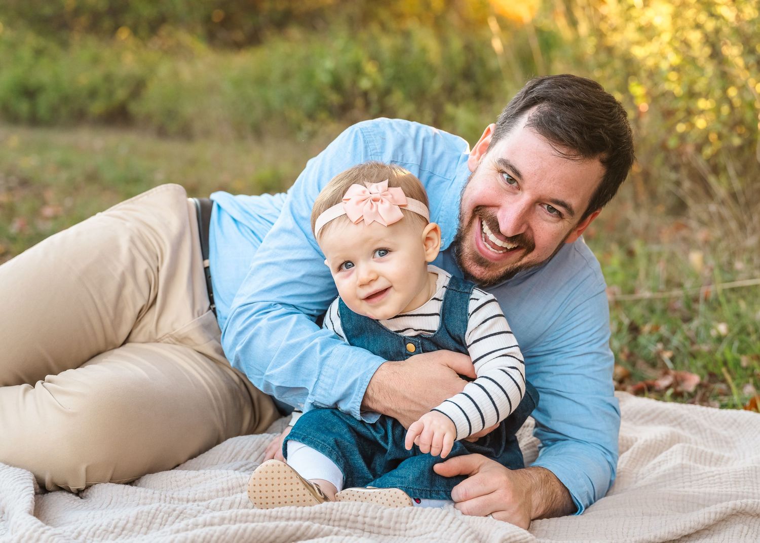 A joyful moment captured on a blanket outdoors during golden hour as autumn leaves color the background.