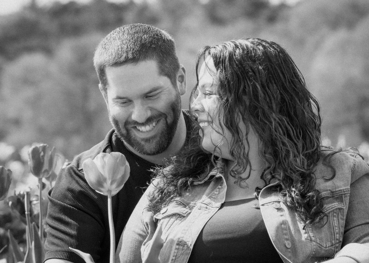Black and white portrait of a happy couple laughing together in an intimate candid moment.