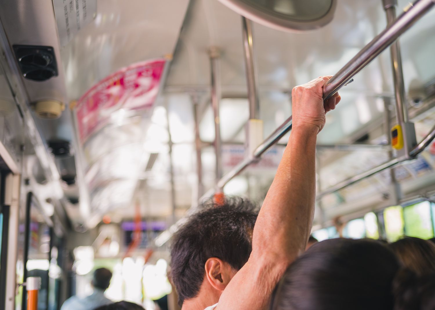 Passengers holding onto handrails inside a crowded public transit vehicle.