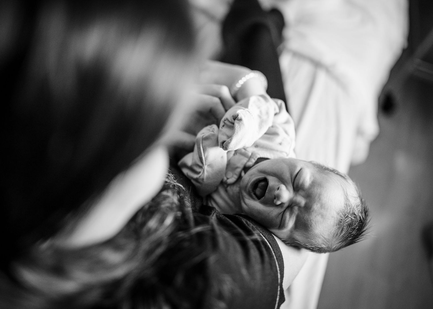 Black and white overhead view of a newborn baby being cradled.