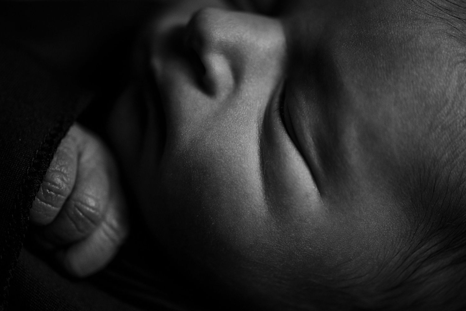 Artistic black and white close-up of sleeping newborn's features.