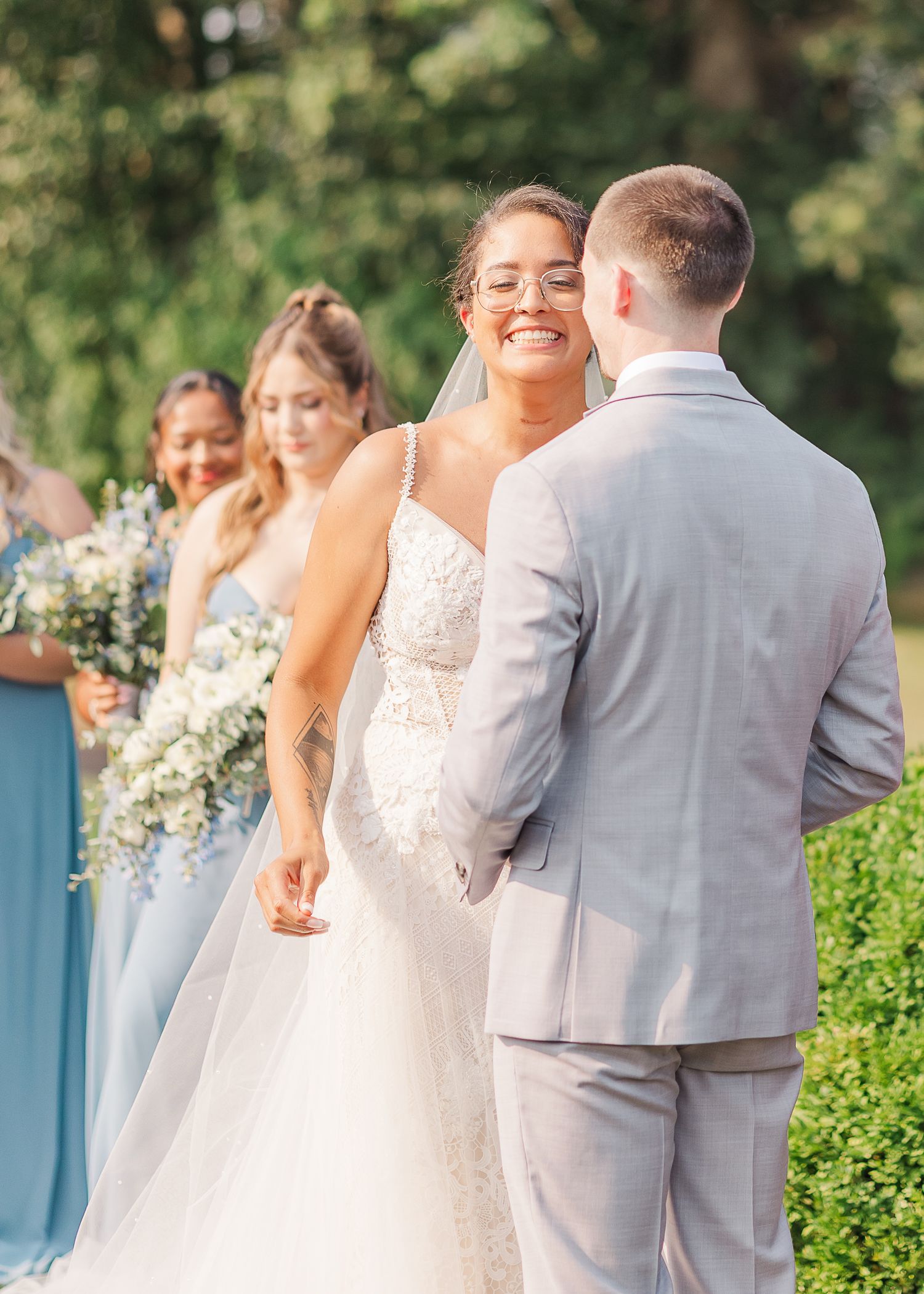 A wedding couple shares a joyful candid moment during their outdoor garden ceremony, with guests looking on.