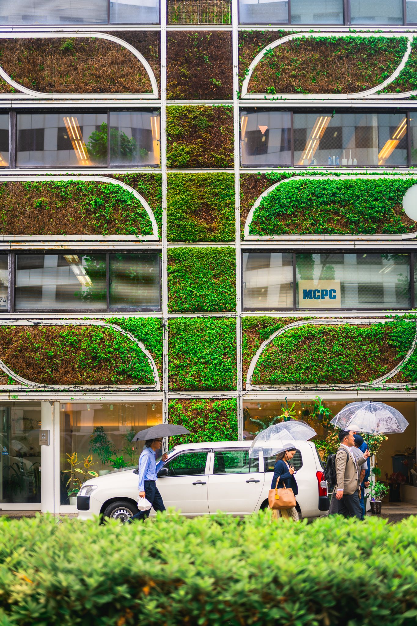 Modern building facade with green living walls and curved window patterns.