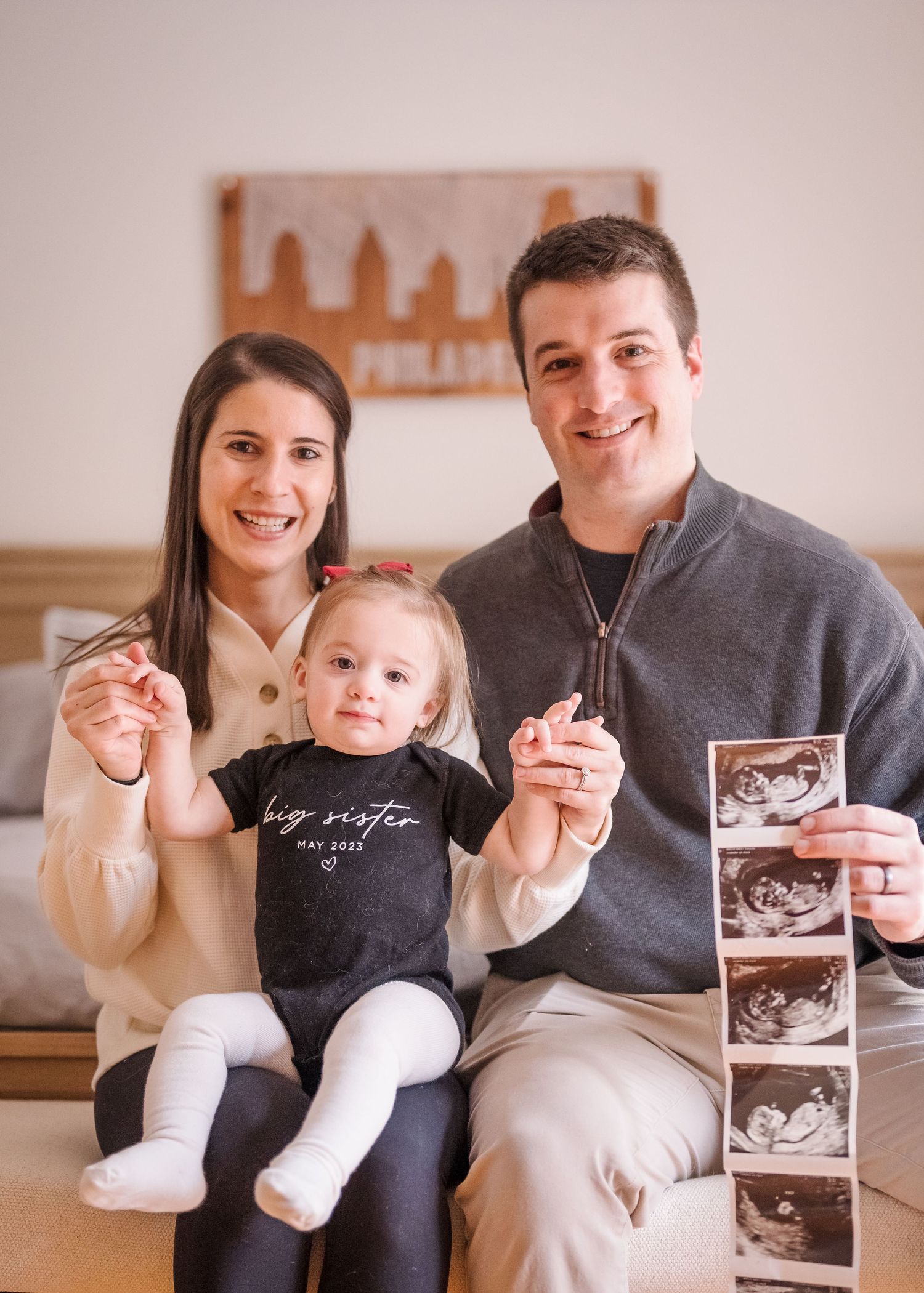 Family announces pregnancy with ultrasound photos and a toddler wearing a big sister shirt.