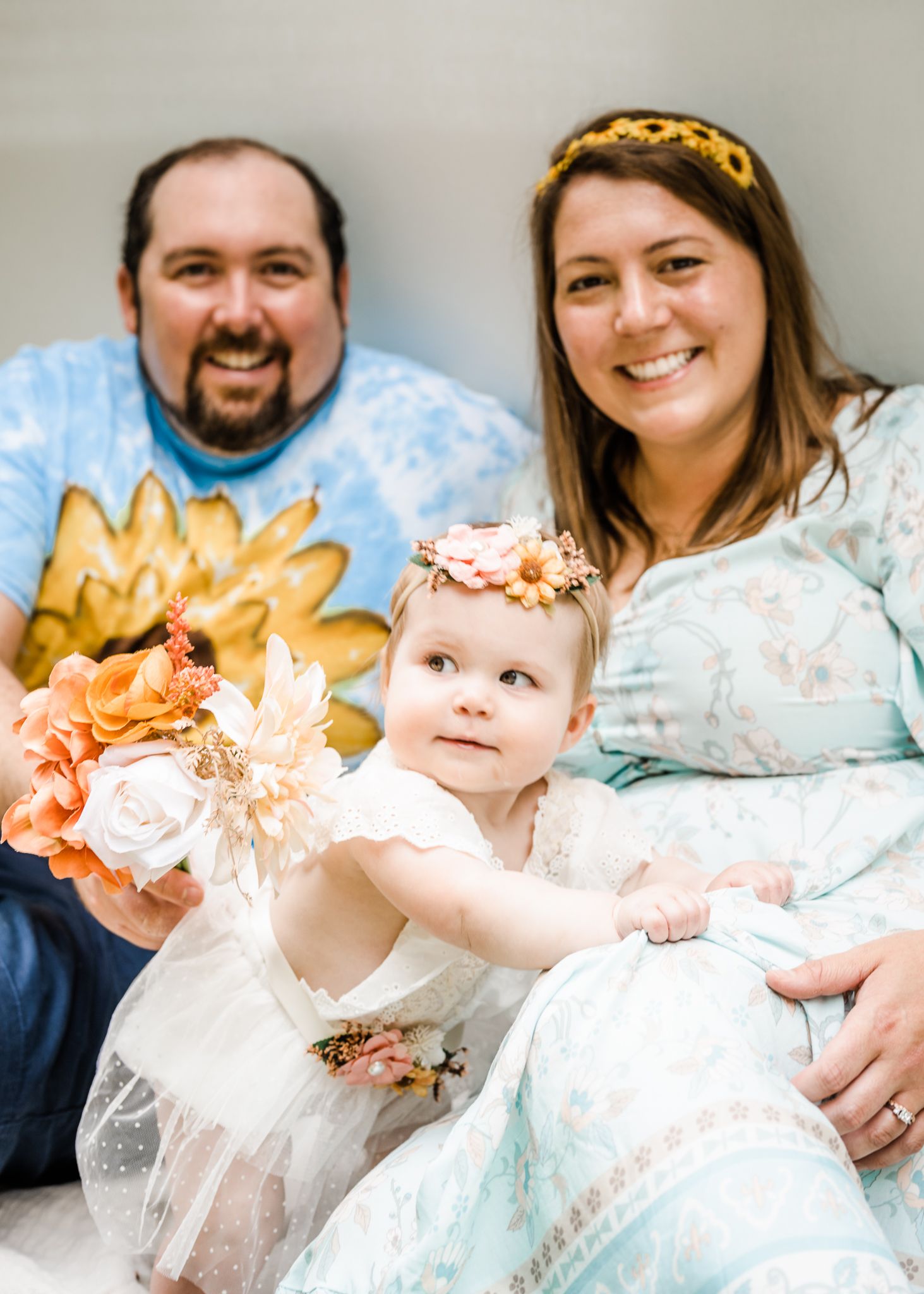 Family portrait with floral decorations and coordinated outfits in blue and white tones.