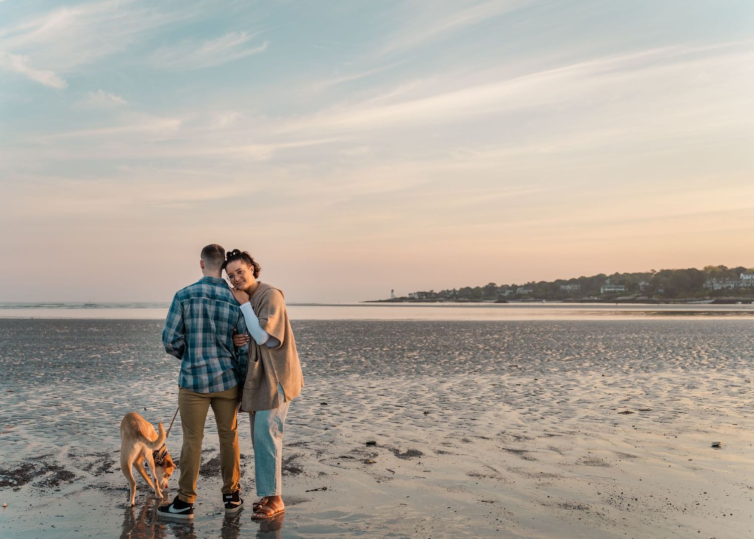 People walking along a sandy beach at sunset while holding hands during a romantic moment.