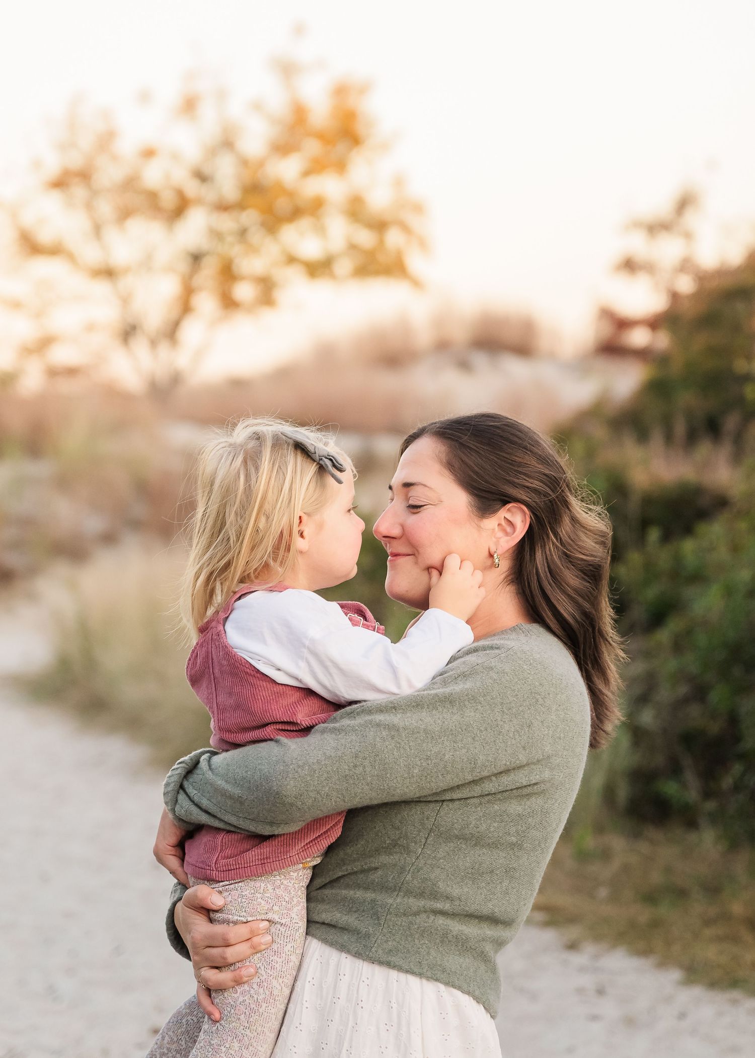 A tender moment between parent and child embracing outdoors in warm sunset light wearing casual clothing.