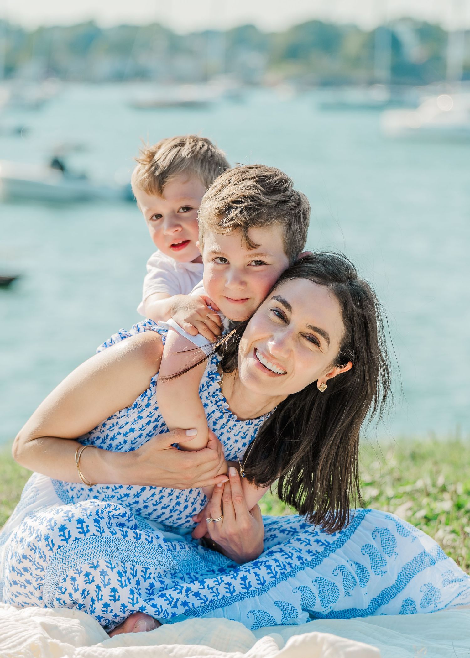A joyful family bonding together on a sunny day by the water wearing coordinating blue outfits.