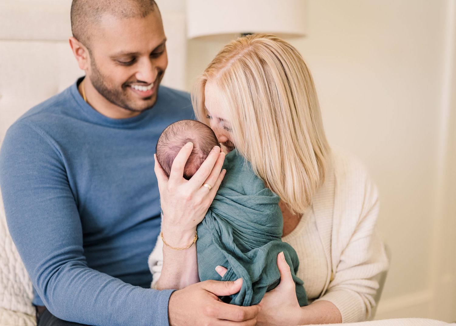 Intimate family moment with baby wrapped in teal swaddle.