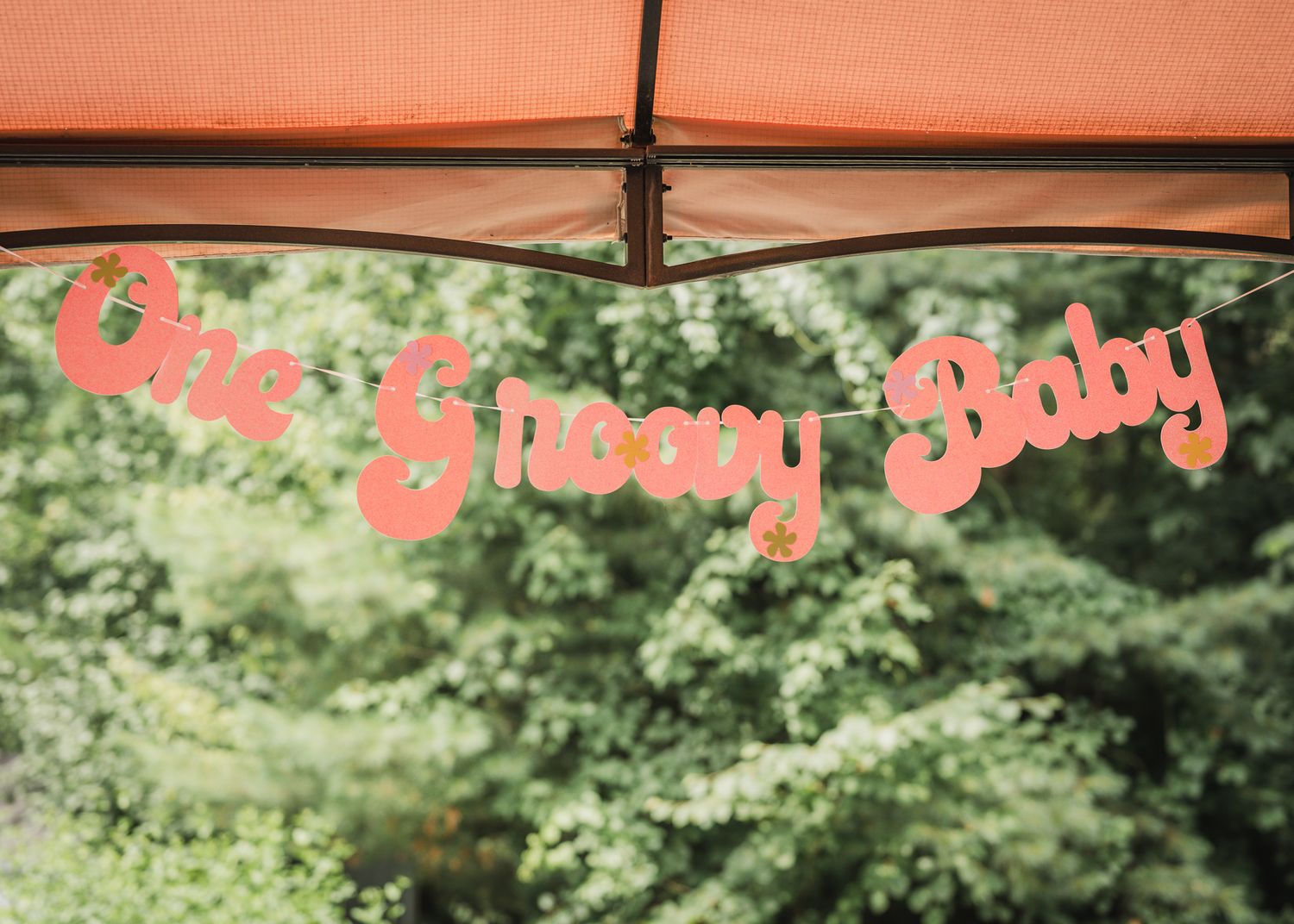 Red decorative banner with text hanging against green foliage background.
