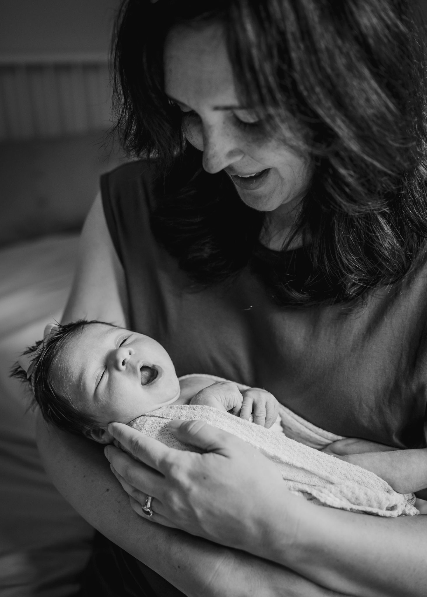 Intimate moment between caregiver and newborn by window light.