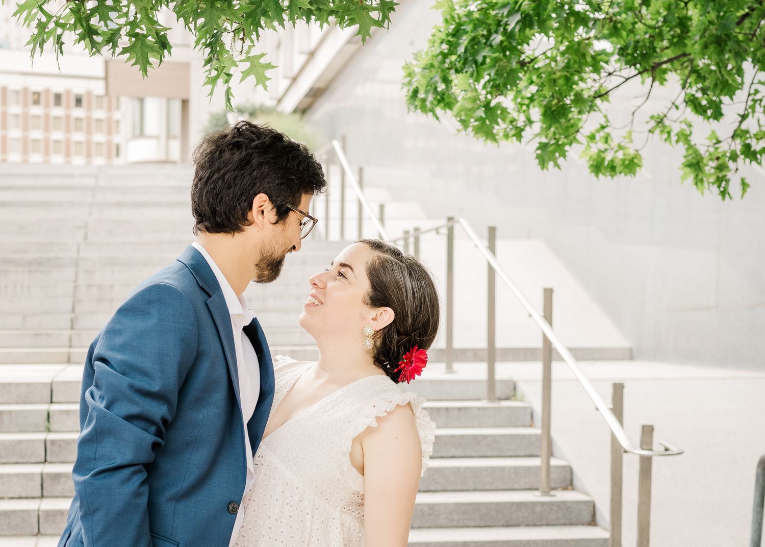Intimate moment shared between couple on white stairs with green foliage above.