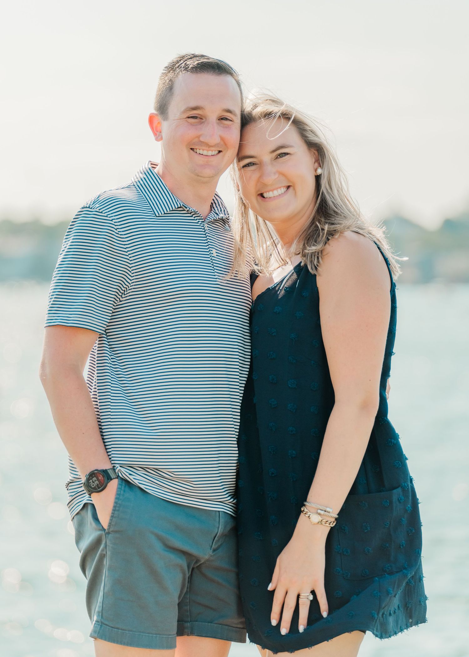 Happy couple embracing outdoors against a bright waterfront backdrop in summer casual wear.