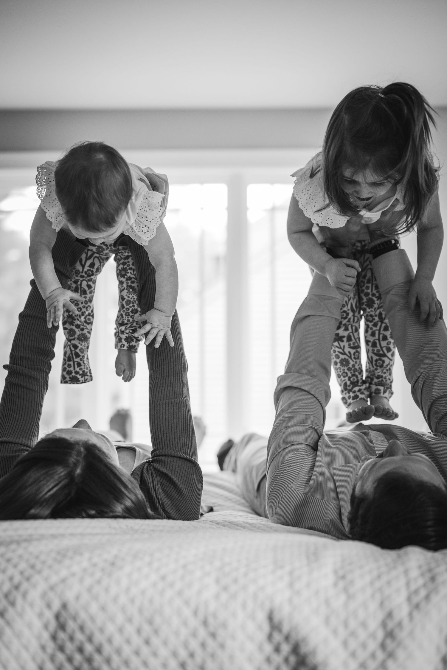 A black and white photo of a family playing and lifting children in the air.