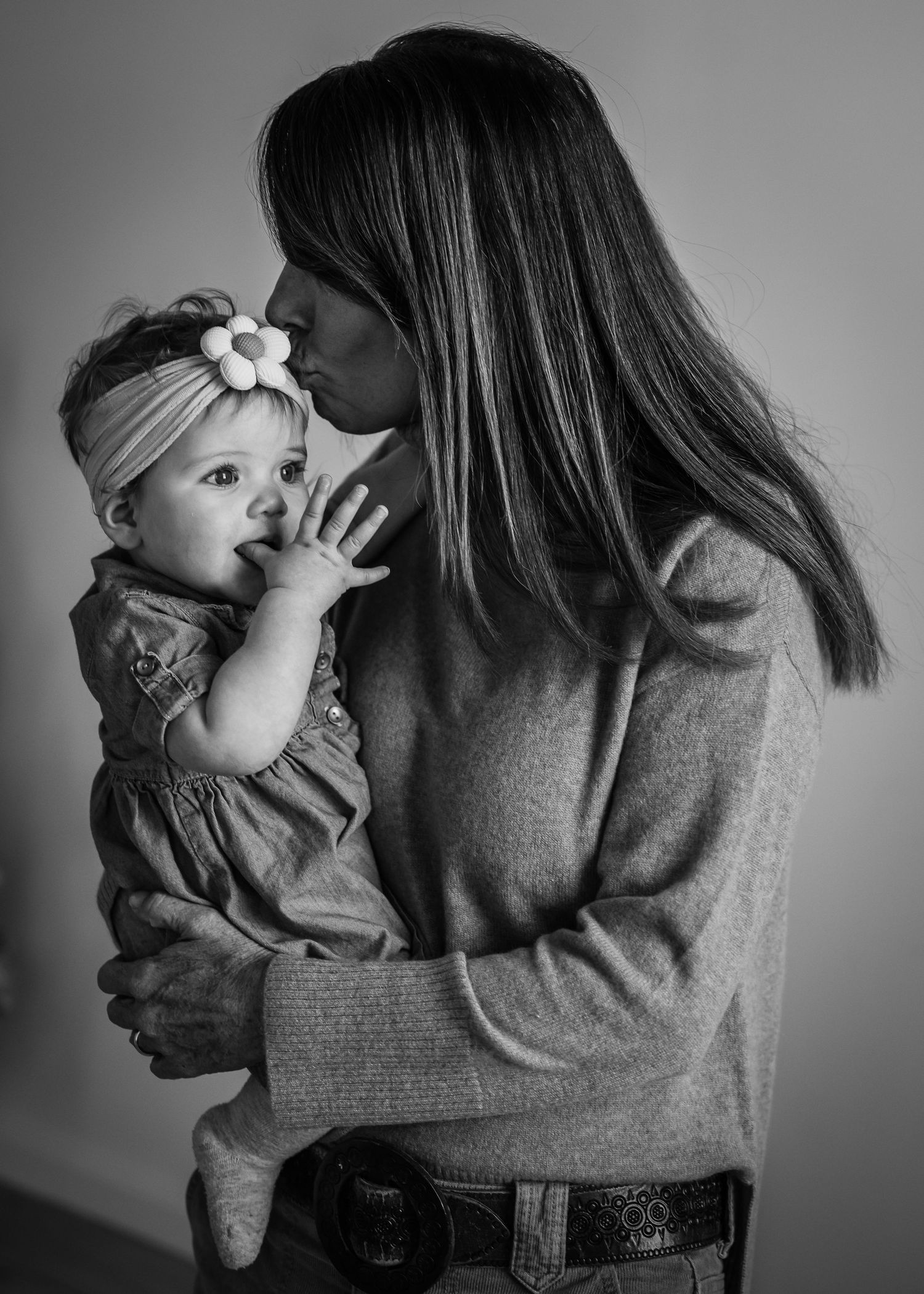 Intimate black and white portrait of parent giving baby a gentle kiss on the head.