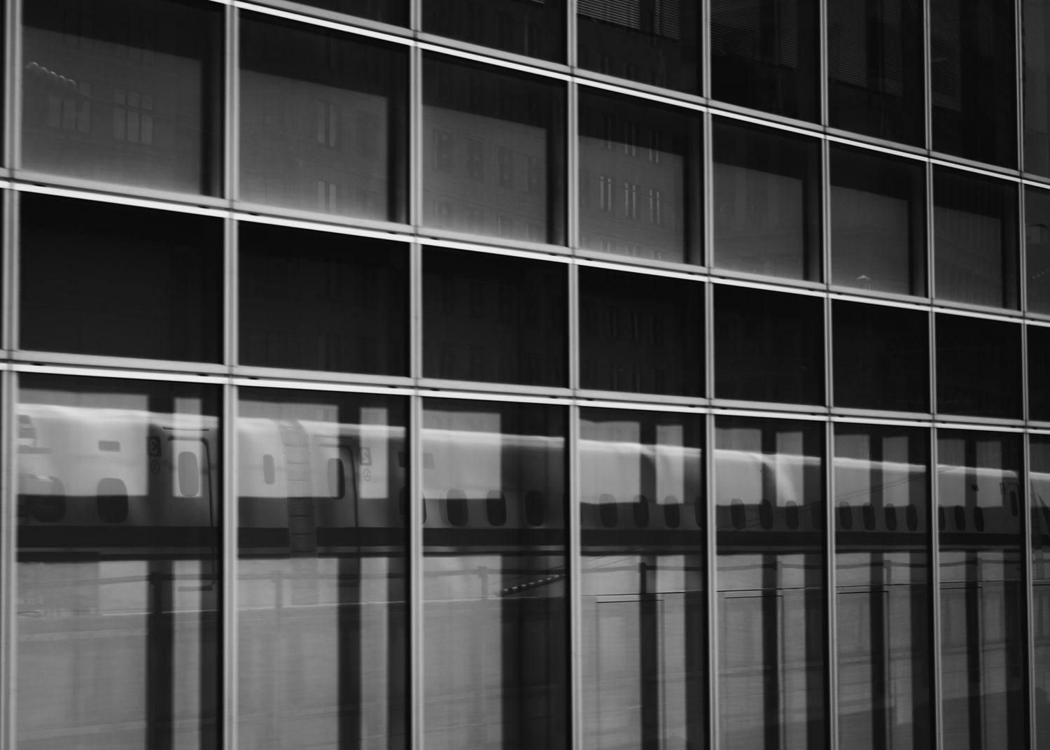 Modern office building facade with repeating pattern of glass windows and metal frames in black and white.
