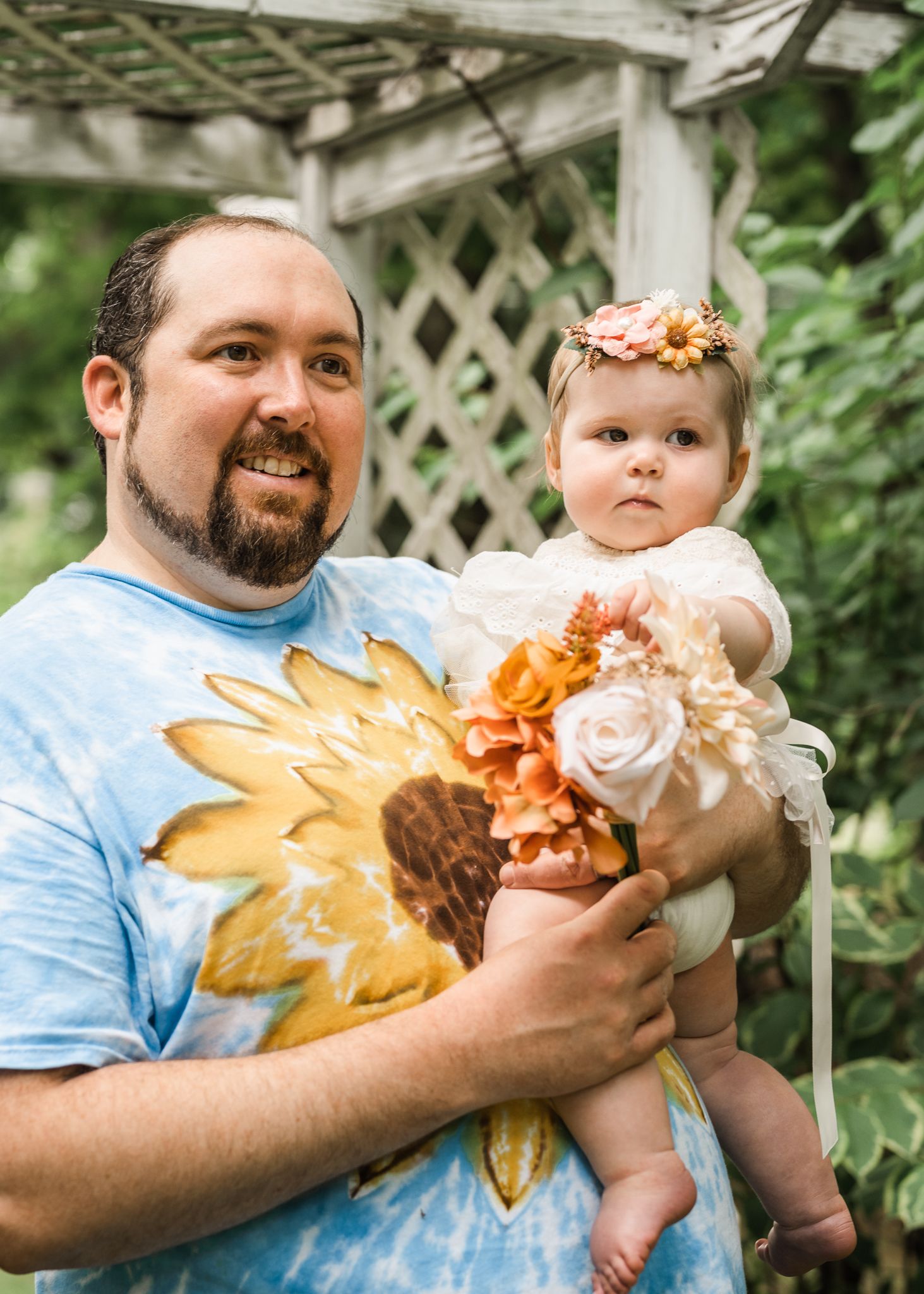 Outdoor portrait under white pergola with greenery backdrop.