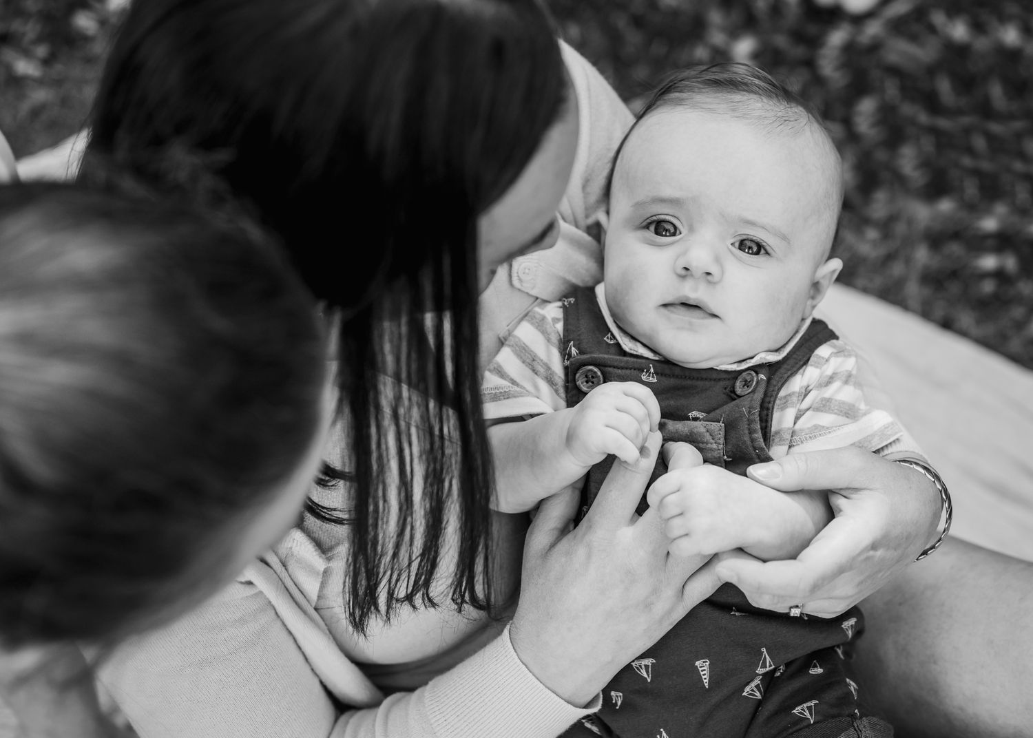 Black and white portrait of tender family moment in garden setting.