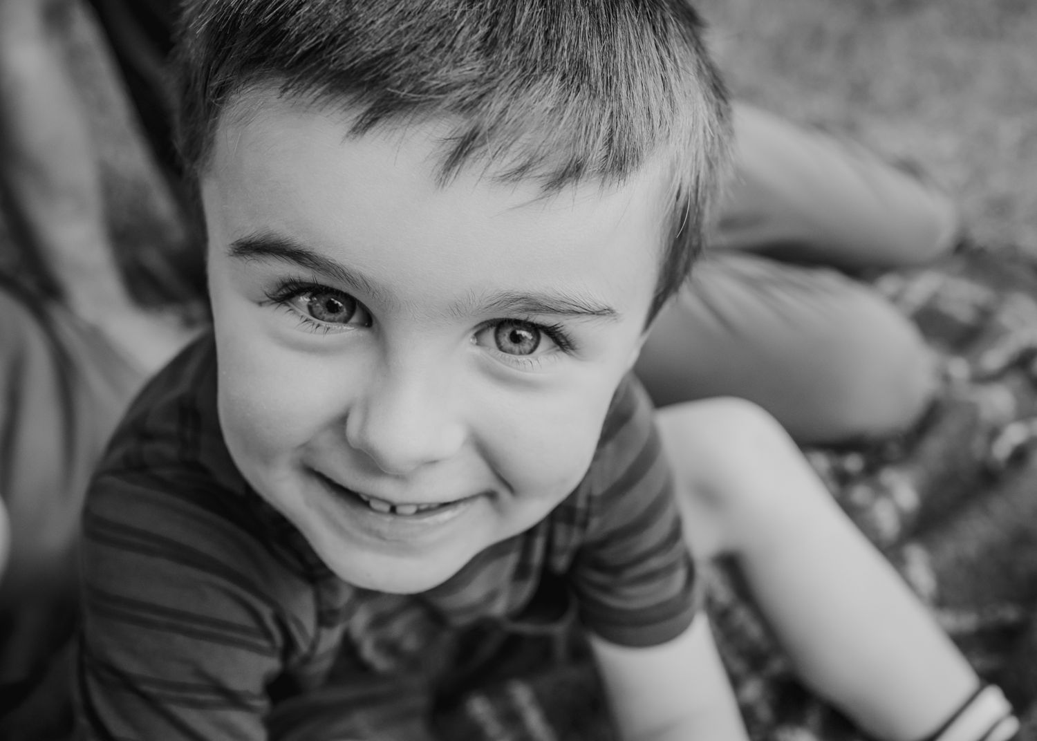 Close-up black and white portrait of child smiling at camera.