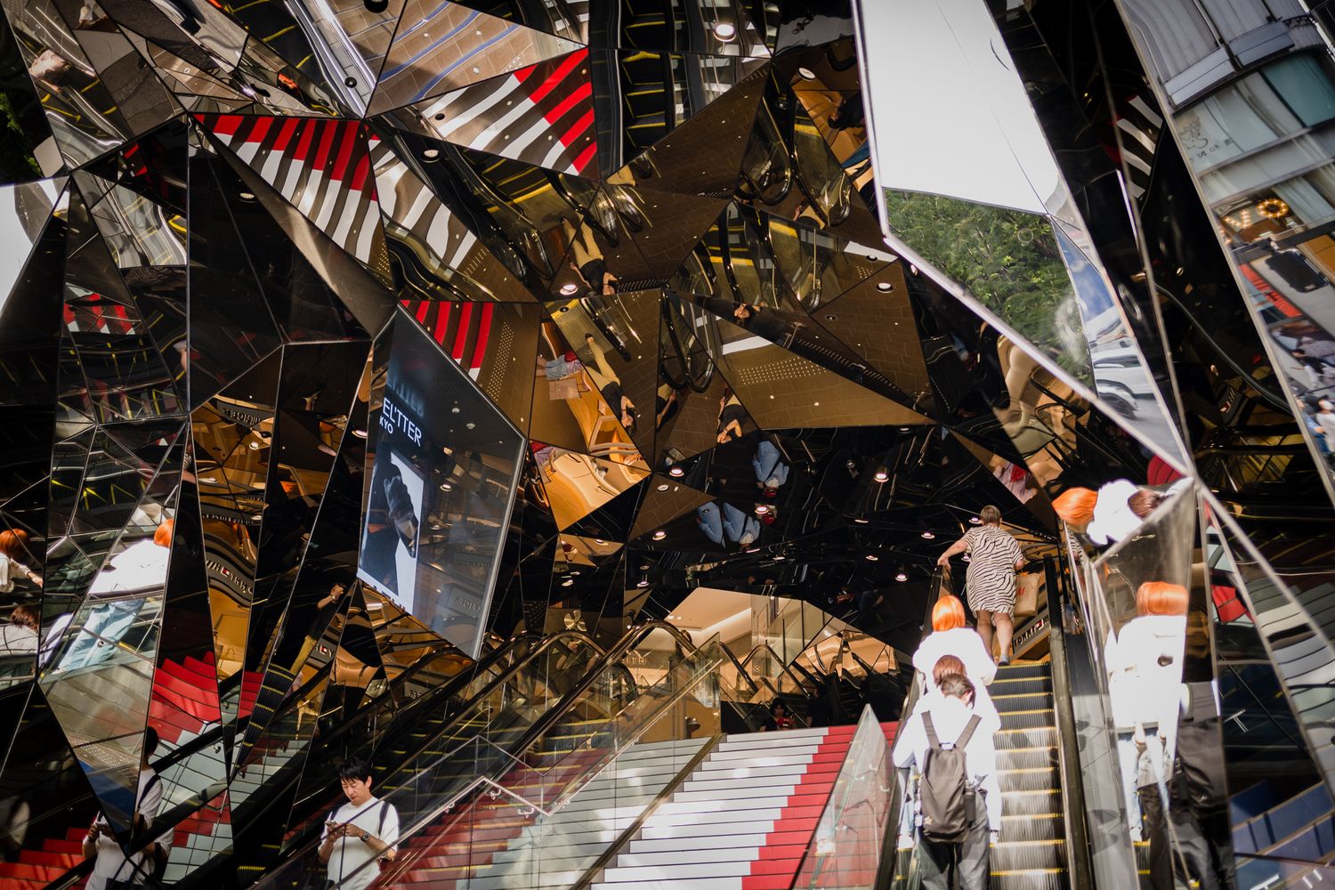 Modern architectural interior with mirrored ceiling and geometric patterns creating a kaleidoscope effect.
