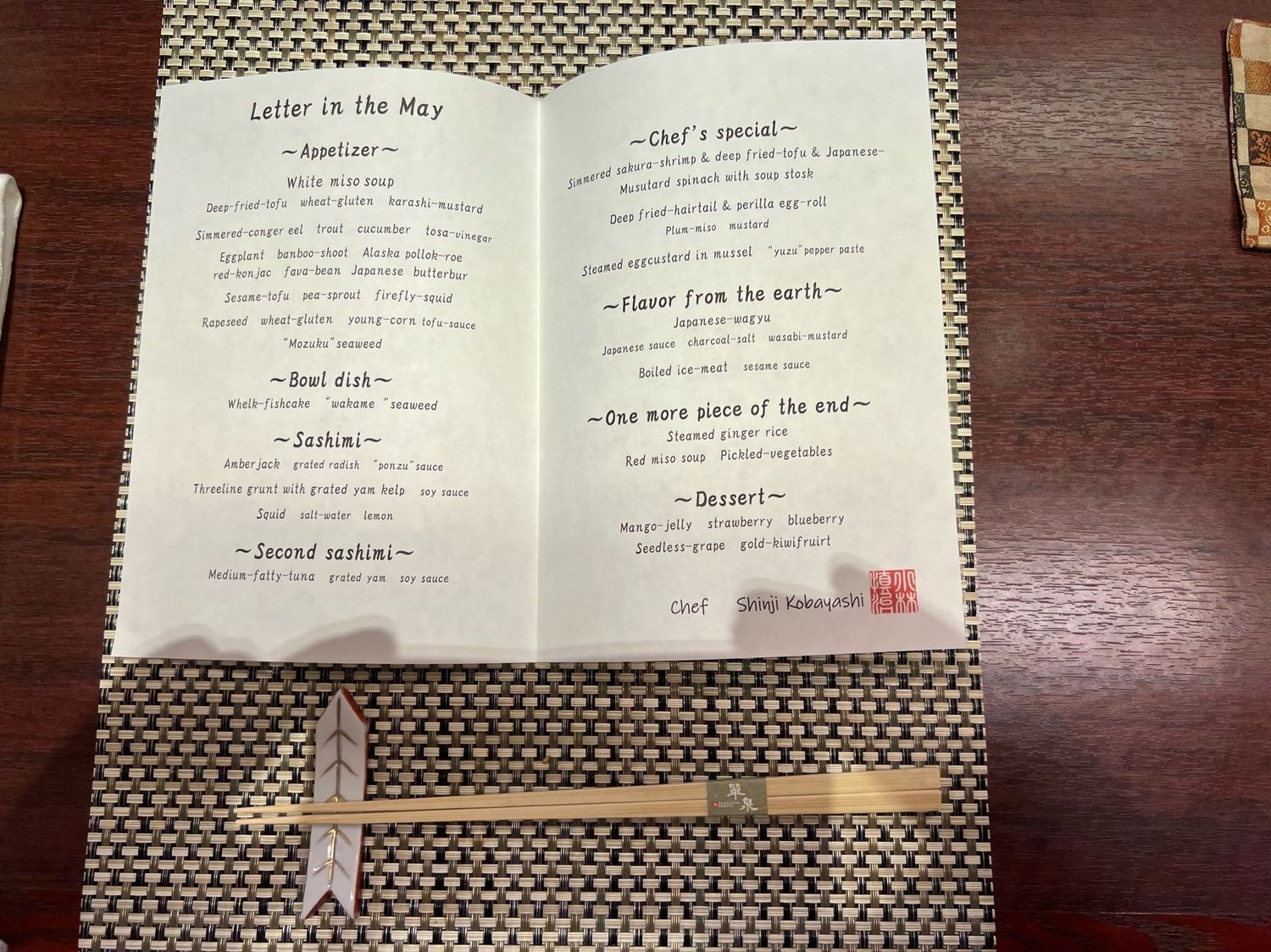 A Japanese restaurant menu open to show multi-course dining options with chopsticks placed below.