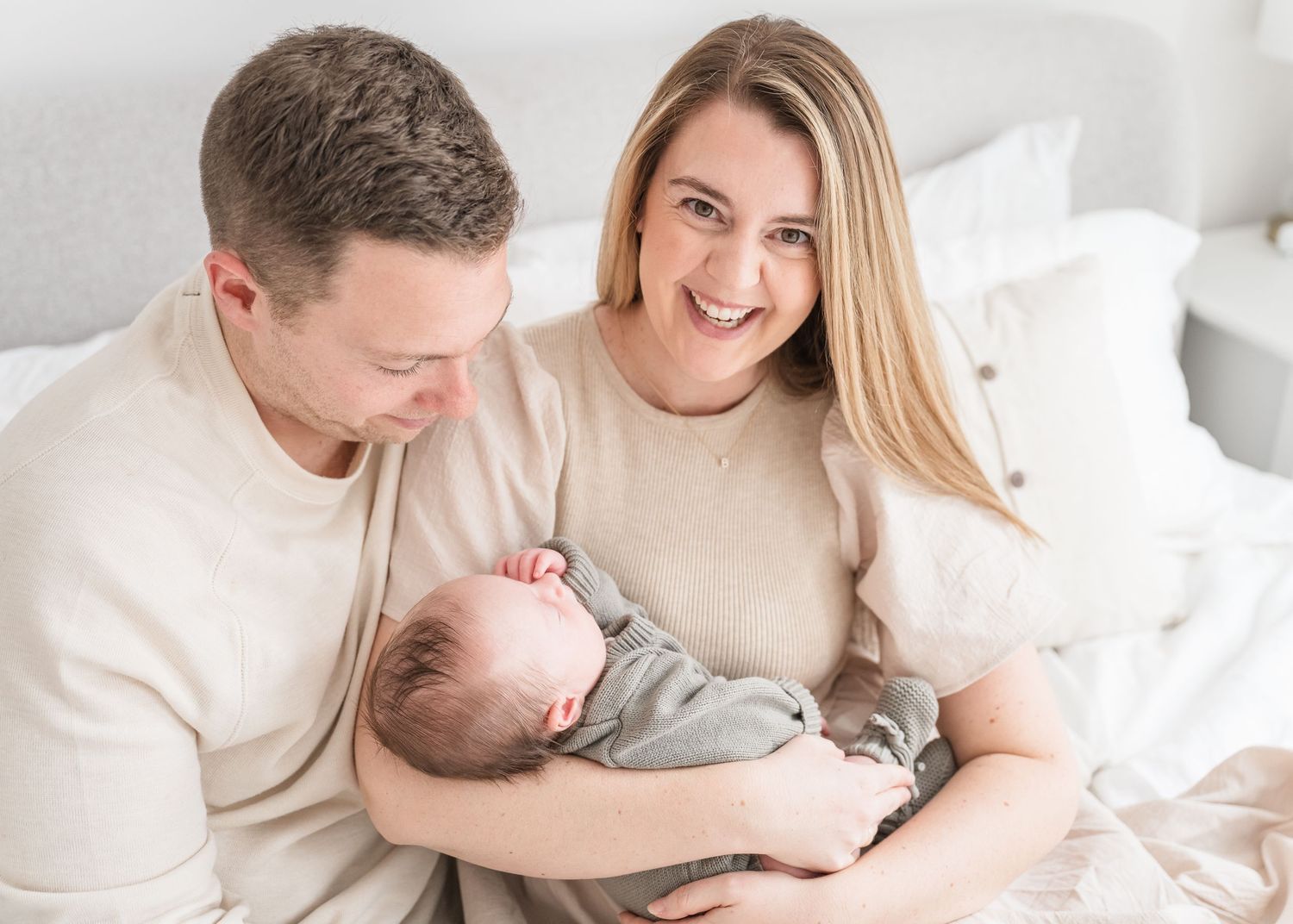 Intimate lifestyle photoshoot showing tender moments between couple in white bedding.