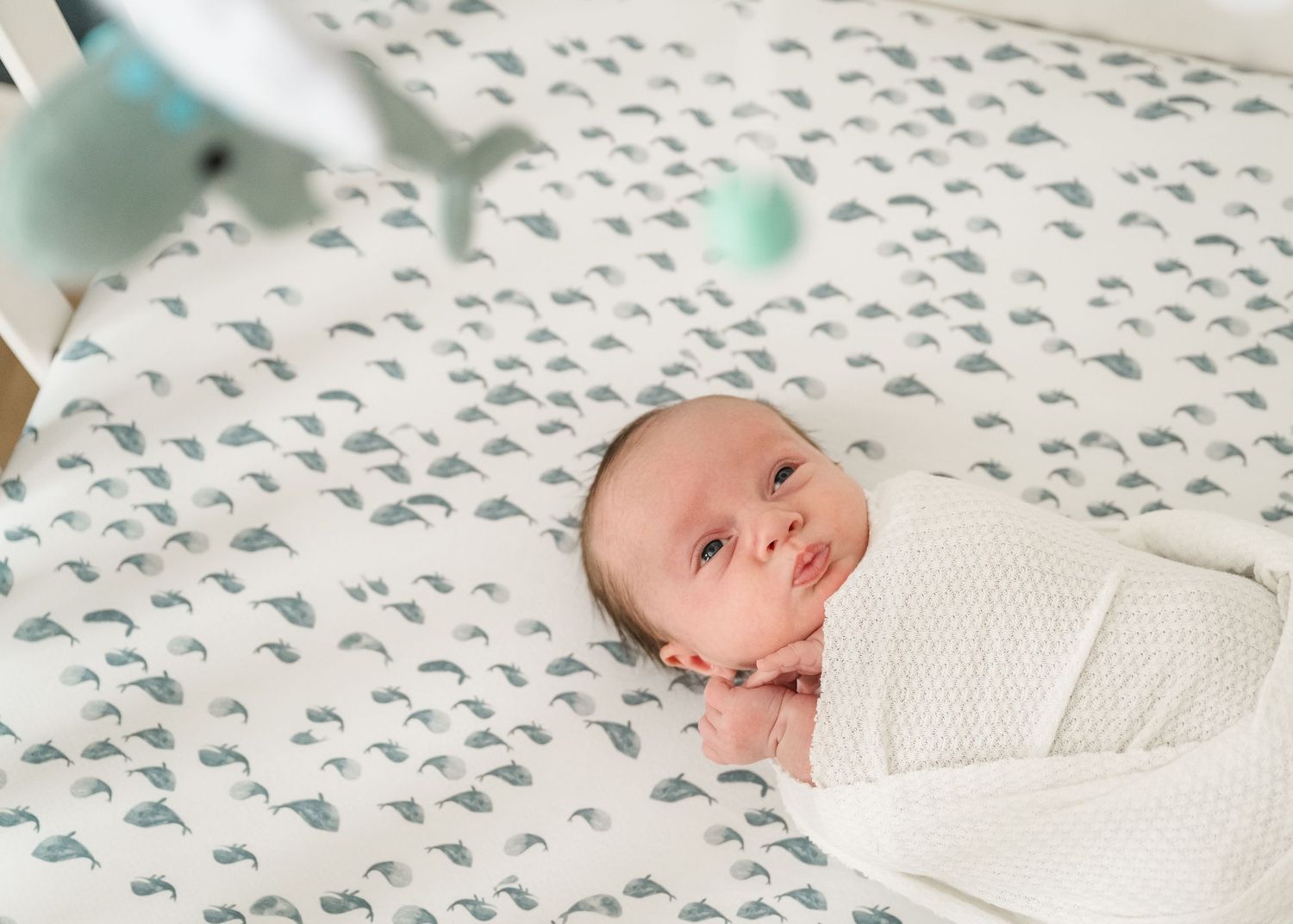Baby resting on patterned bedding in soft natural light.