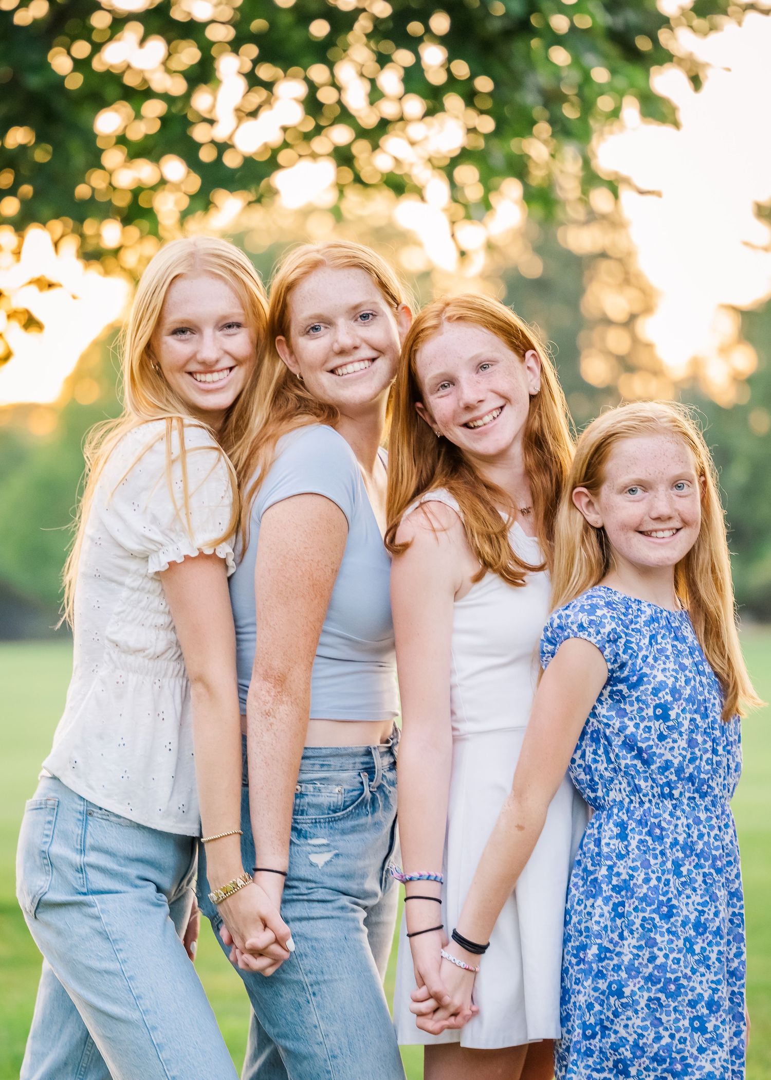 Four redheaded siblings pose in a line wearing casual summer outfits during sunset.