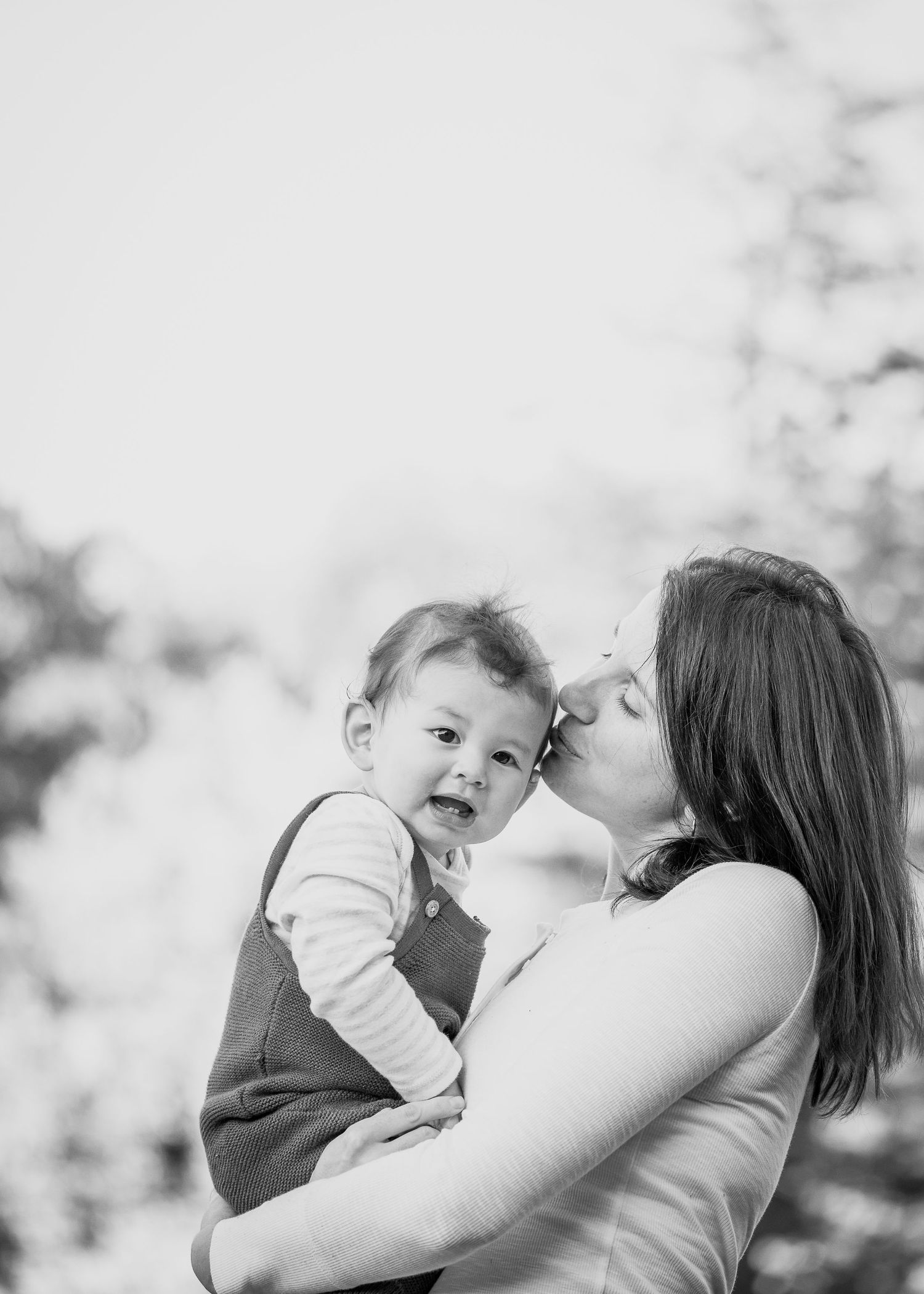 A tender black and white portrait of a parent sharing an affectionate moment with their baby.