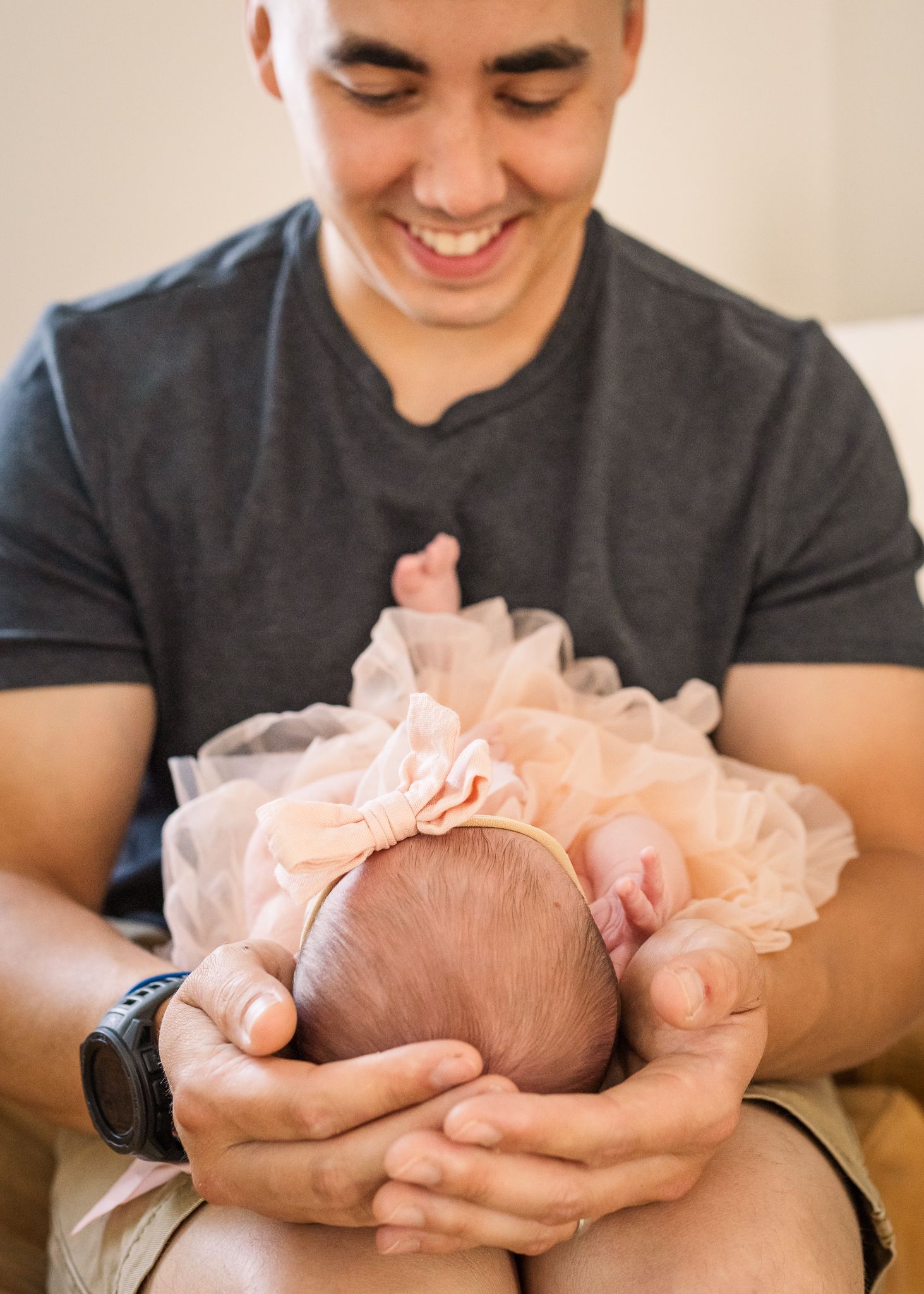 Gentle moment with newborn in peach tulle dress against dark clothing.