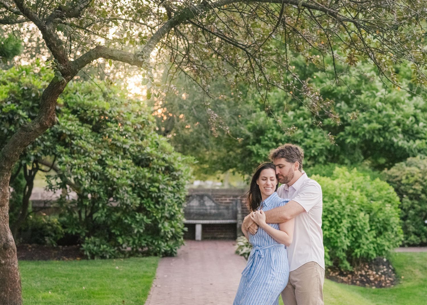 Romantic couple embrace in lush garden setting during golden hour.