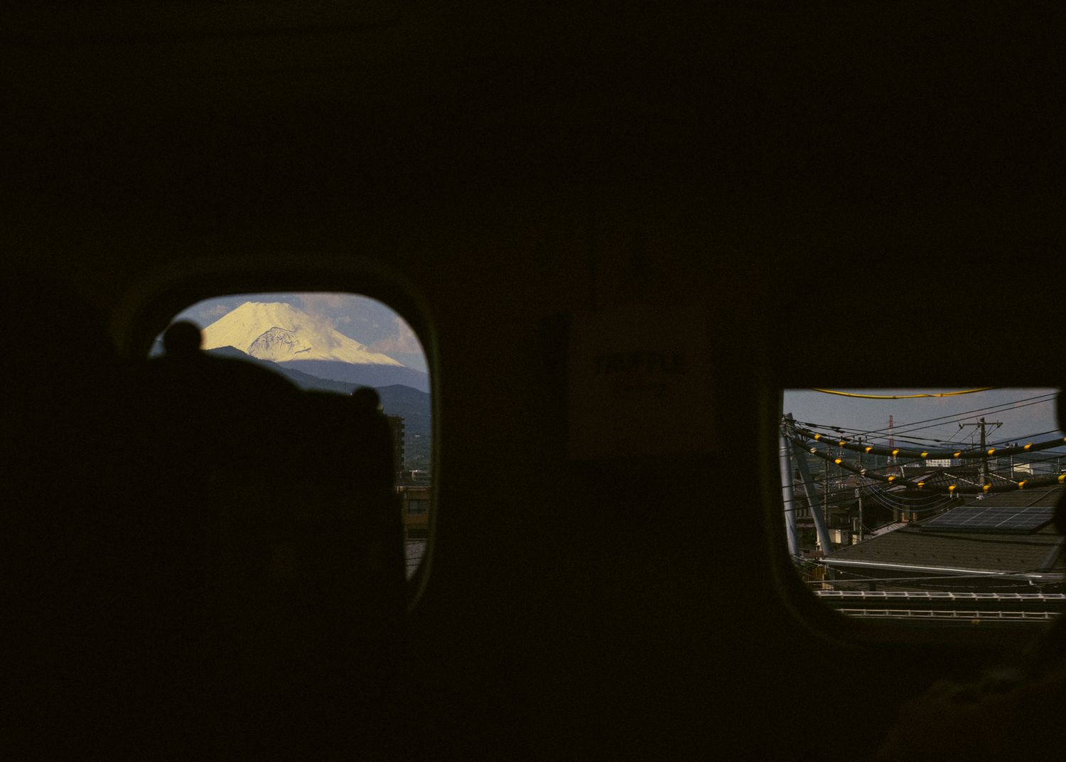 View through dark train or airplane windows showing glimpses of an urban landscape.