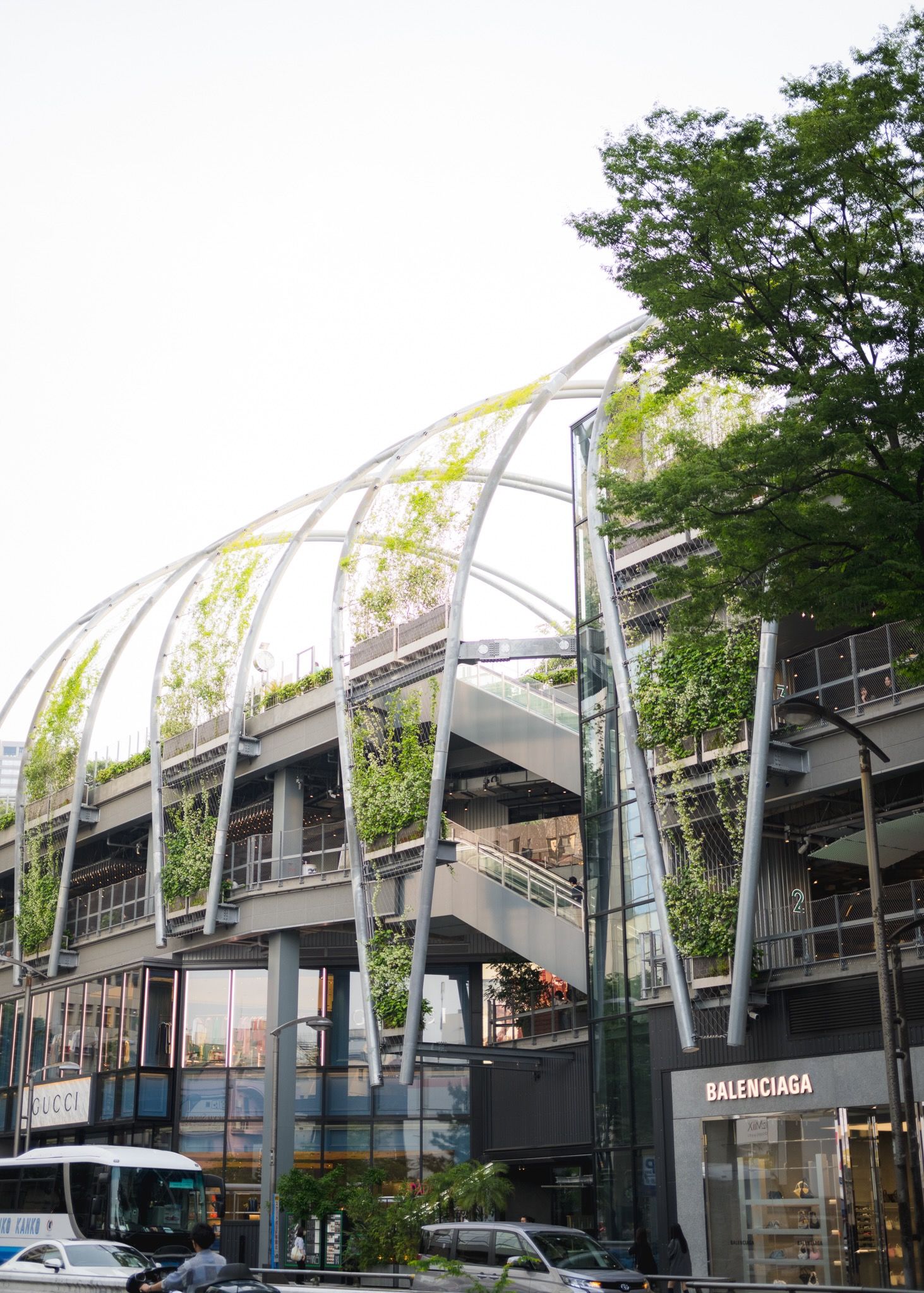 Modern glass-domed architectural structure with Balenciaga store front and trees.
